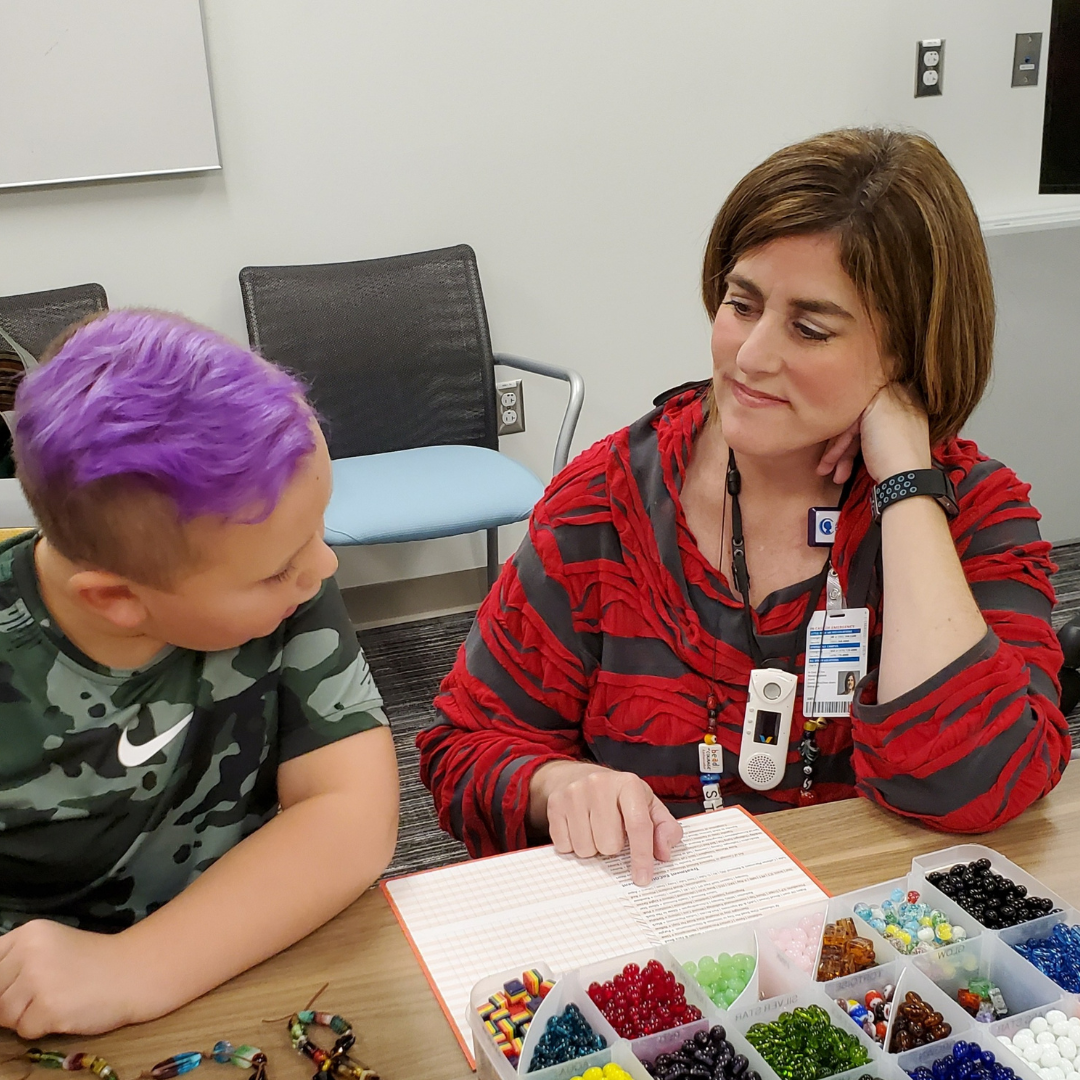 Child receiving Beads of Courage materials from a Child Life Specialist