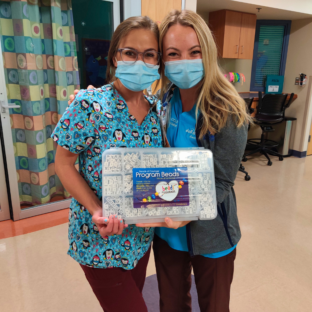 Hospital staff holding up a Beads of Courage materials box. Wearing masks but seems like they are smiling